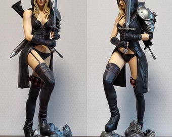 May include: A detailed statue of a female warrior in a black hooded cloak, holding a sword. She stands on a defeated foe, with the words "Sweet Pea" on the base. The figure is in a dynamic pose, with intricate details in the clothing and armor.