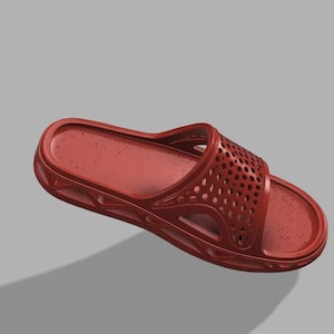 May include: A single red slide sandal with a perforated strap. The sandal is made of a solid material and has a contoured footbed. The design includes a series of small holes on the top strap for ventilation. The sandal is shown against a grey background.
