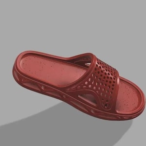 May include: A single red slide sandal with a textured footbed and a perforated strap. The sandal is made of a solid material and is designed for casual wear. The shoe is shown on a grey background.