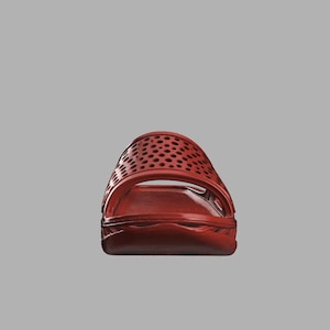 May include: A red slide sandal with a perforated upper. The sandal features a molded footbed and a single strap. The colour is a deep, rich red, and the design is simple and modern.