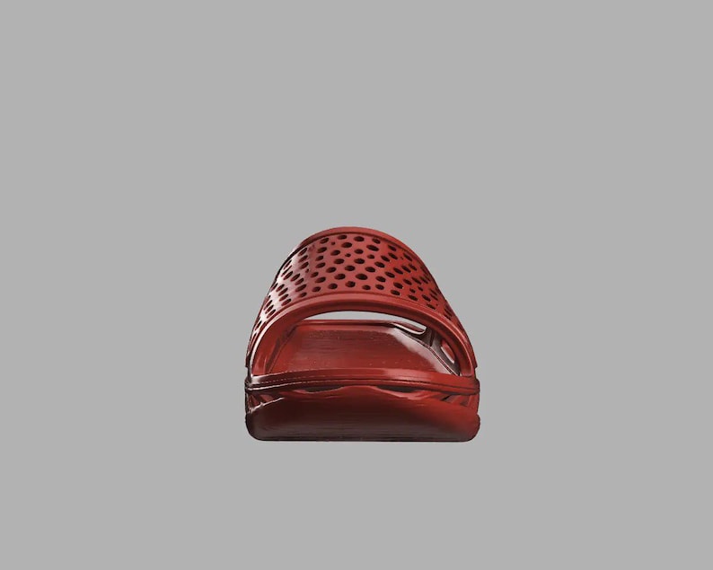 May include: A red slide sandal with a perforated upper. The sandal features a molded footbed and a single strap. The colour is a deep, rich red, and the design is simple and modern.
