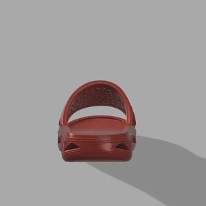 May include: A single red slide sandal. The sandal features a textured footbed and a perforated strap. The sole has a sculpted design. The sandal is set against a grey background.