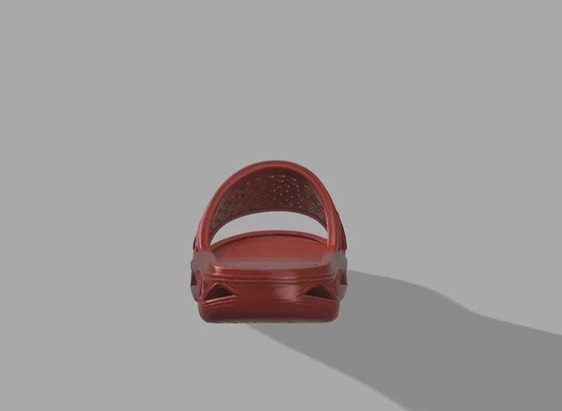 May include: A single red slide sandal. The sandal features a textured footbed and a perforated strap. The sole has a sculpted design. The sandal is set against a grey background.