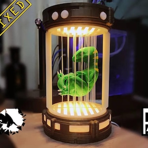 Puede incluir: Lámpara futurista con una figura de dinosaurio verde suspendida dentro de un cilindro iluminado. La base y la parte superior son de color marrón oscuro. La palabra "REMIXED" está en un cuadro amarillo en la esquina superior izquierda. La lámpara mide unos 30 cm de alto.