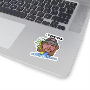 May include: A sticker featuring a cartoon image of a person with a beard and a hat. The text "I SURVIVED" is above the image, and "GOOB LAGOON" is below. The sticker is on a laptop.