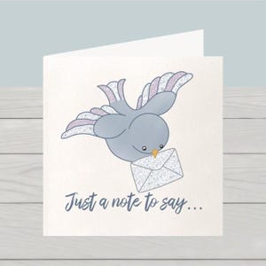 May include: A greeting card with a cartoon bird delivering a letter. The bird is grey with patterned wings. The envelope has a floral design. The text "Just a note to say..." is written in a script font.