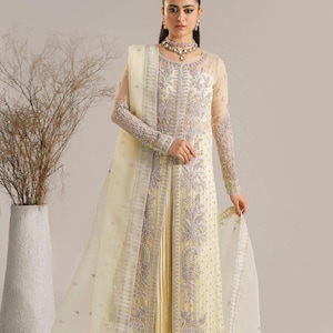 Puede incluir: Un vestido amarillo bordado con una superposición transparente y un dupatta a juego. El vestido tiene una silueta larga y fluida y está adornado con intrincados patrones florales.