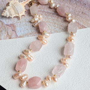 Puede incluir: Un collar que presenta una alternancia de cuentas de cuarzo rosa facetadas y perlas de agua dulce blancas irregulares. Las cuentas están separadas por pequeños espaciadores de metal dorado. Una pequeña concha texturizada se sitúa cerca del cierre.
