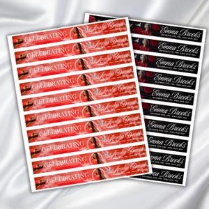 May include: Two sheets of memorial stickers. One sheet features red banners with the text "CELEBRATING" and the name "Amelia David." The other sheet has black banners with the name "Emma Brooks." Both sheets include dates.