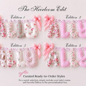 May include: Four fabric letter banners spelling ALLY, labeled Edition 1 through 4. Each banner features stuffed letters in floral, gingham, and teddy bear patterns, suspended from a floral ribbon with pink satin bows at both ends.