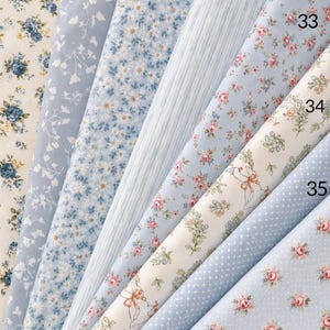 May include: A collection of eight fabric swatches labeled 29 through 36, featuring various patterns including blue and yellow floral prints, white line drawings, vertical stripes, and white polka dots on light blue and cream backgrounds.