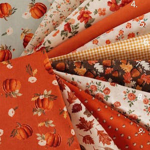 May include: A collection of eleven fabric swatches featuring autumn-themed patterns including pumpkins, floral prints, gingham, acorns, and fall leaves in shades of orange, brown, cream, and sage green, labeled Pumpkin Spice Cafe Collection.