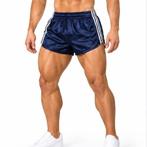Könnte beinhalten: Dunkelblaue Sportshorts mit glänzendem, satinartigem Finish. Die Shorts verfügen über einen elastischen Bund und drei vertikale weiße Streifen an jeder Seite. Der Saum ist geschwungen und der Stoff hat eine glatte, reflektierende Textur.