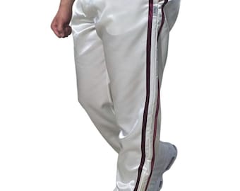 May include: White satin track pants with a drawstring waist and burgundy stripes down the sides. The pants have a relaxed fit and are paired with white sneakers. The overall style is casual and sporty.
