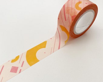 May include: A roll of decorative washi tape with a peach background and a repeating pattern of orange and pink geometric shapes. The tape is unrolled, revealing the design. The tape is ideal for scrapbooking, journaling, and other craft projects.