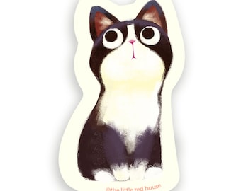 May include: A black and white cat with large, round eyes looks up with a surprised expression. The cat is sitting on a light yellow background. The text "©the little red house" is at the bottom of the image.
