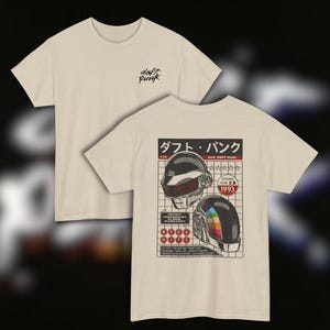 Puede incluir: Dos camisetas beige. Una muestra el texto "daft punk" en escritura negra. La otra presenta un gráfico de dos cascos de robot con texto japonés y el año 1993. Los cascos tienen detalles en rojo, negro y arcoíris.