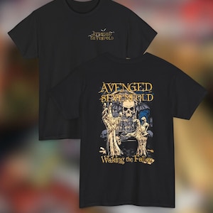 Peut inclure: T-shirts noirs avec le nom du groupe "Avenged Sevenfold". L'un des t-shirts porte le logo du groupe sur la poitrine. L'autre présente un graphisme de crâne, de mains et les mots "Waking the Fallen".
