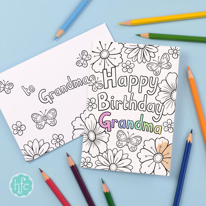 A black and white card and envelope lie on a pale blue background with colouring pencils scattered around. The card has been partially coloured in. The card has bubble writing with the message "Happy Birthday Grandma" and is surrounded by drawings of flowers and butterflies.
