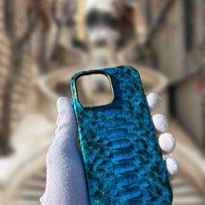 May include: A teal blue snakeskin phone case with a camera cutout.