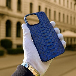 May include: A blue snakeskin phone case with a textured pattern. The case is designed for a smartphone with a camera lens cutout.