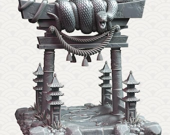 May include: A gray stone torii gate with a coiled snake sculpture on top. The gate is decorated with rope and tassels. The base of the gate is surrounded by rocks and plants.