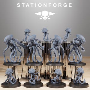 May include: A collection of gray alien-like figurines with multiple tentacles and detailed head structures. The figurines are displayed on black circular bases and a tiered platform. The text "STATIONFORGE" is at the top.
