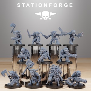 May include: A collection of gray miniature figurines of Orcs, each holding weapons like axes, knives, and guns. The figurines are displayed on clear stands, with the text "STATIONFORGE" and a skull logo at the top.