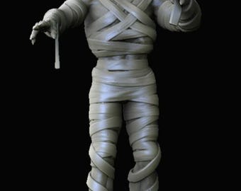 May include: A light gray, monochromatic figurine of a mummy with a skeletal face and exposed teeth. The figure is wrapped in multiple layers of bandages that crisscross over the torso, arms, and legs, with loose ends hanging from the hands.