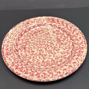 Puede incluir: Una taza de cerámica blanca con asa negra y el texto "But First, Coffee" en negrita negra. La taza se encuentra sobre un fondo borroso, sugiriendo un ambiente acogedor.