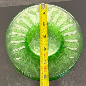 Puede incluir: Un plato redondo de vidrio verde transl&uacute;cido con un patr&oacute;n de hojas en relieve en toda su superficie. Una cinta m&eacute;trica amarilla est&aacute; colocada en el centro, indicando un di&aacute;metro de aproximadamente 15,24 cm para este plato decorativo.