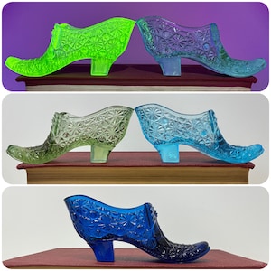 Può includere: Una collezione di statuette di scarpette di vetro in vari colori: verde neon, viola, trasparente, azzurro e blu scuro. Ogni scarpetta presenta un motivo strutturato a forma di diamante e un piccolo tacco. Le scarpette sono esposte su una superficie rossa.