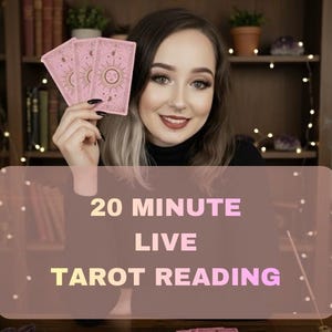 May include: A woman holding pink tarot cards with sun and star designs. The image includes the text "20 MINUTE LIVE TAROT READING". Two lit candles and a crystal ball are also visible.