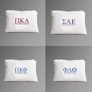 Pode incluir: Quatro almofadas brancas com letras gregas e nomes de fraternidades impressos. A almofada superior esquerda tem "ΠΚΑ" e "PI KAPPA ALPHA" em bordô. A almofada superior direita tem "ΣΑΕ" e "SIGMA ALPHA EPSILON" em roxo.
