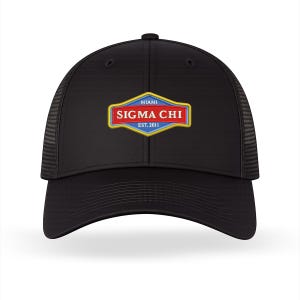 Puede incluir: Gorra de camionero negra con parte trasera de malla y visera curva. El panel frontal presenta un emblema rectangular con el texto "MIAMI SIGMA CHI EST. 2011" en rojo, azul y dorado.