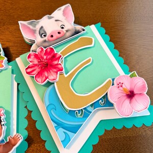 May include: A layered banner with a teal scalloped edge, featuring a gold letter "E", a cartoon pig, and pink and red hibiscus flowers. The banner has a tropical theme with blue wave details.