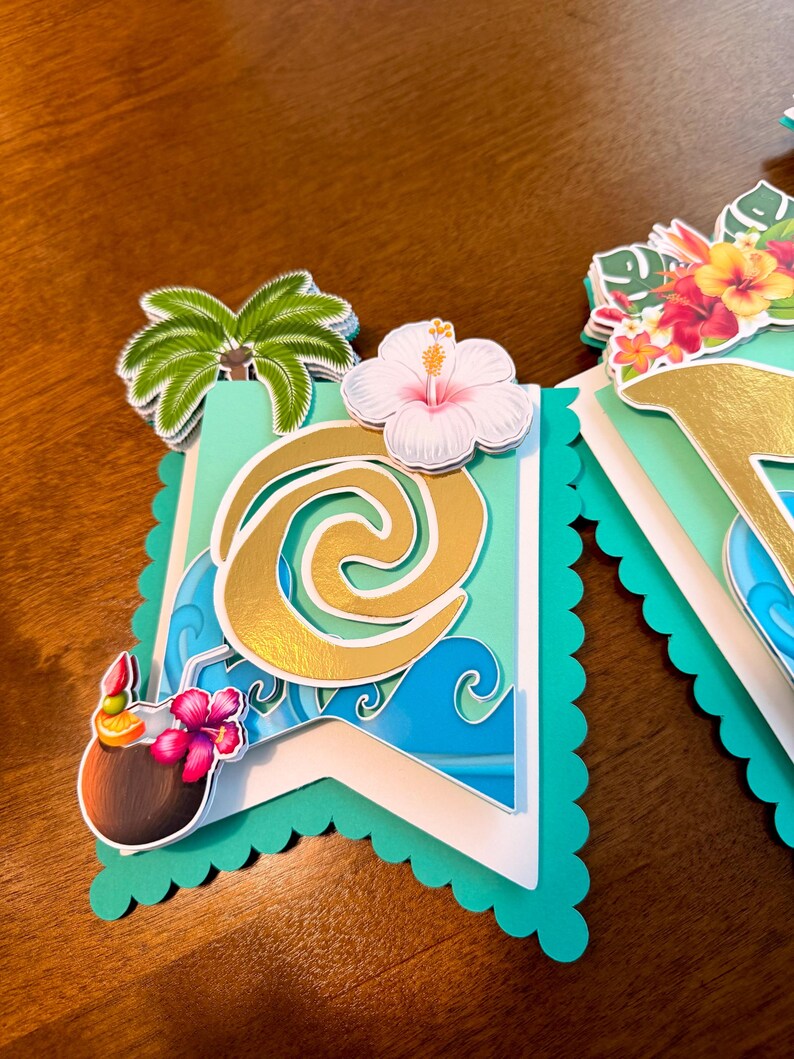 May include: A banner with a tropical theme, featuring a teal scalloped edge. The banner includes a gold design, blue waves, a palm tree, a white hibiscus flower, and a coconut drink with a flower. The banner is layered with white and teal paper.