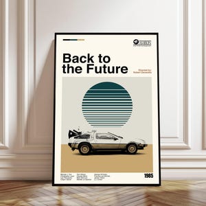 Può includere: Un poster incorniciato con il titolo del film "Ritorno al futuro". Il poster ha uno sfondo color crema con una grafica turchese e bianca di un sole e un'auto DeLorean. L'anno "1985" è visualizzato in basso.