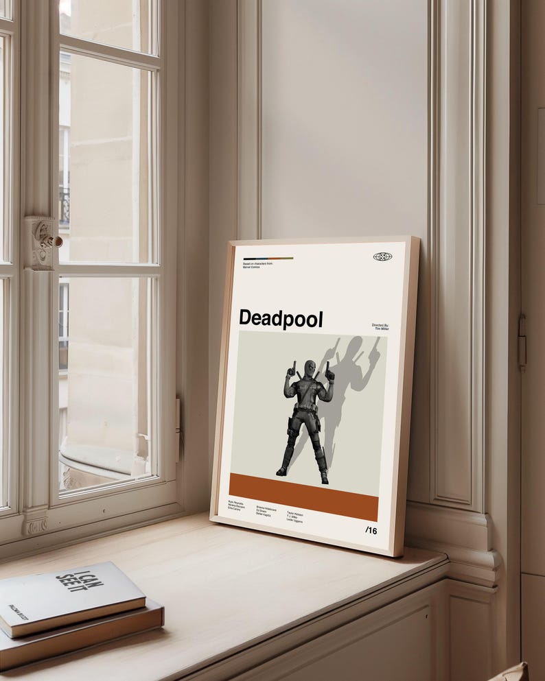 Puede incluir: Un p&oacute;ster enmarcado con la palabra "Deadpool" en negro. El p&oacute;ster muestra una ilustraci&oacute;n en escala de grises del personaje de Deadpool sosteniendo dos armas, con una sombra detr&aacute;s. El fondo es de color beige claro.