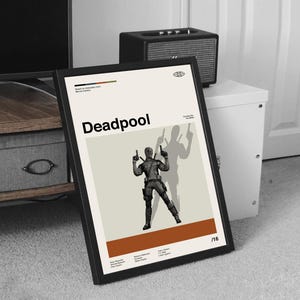 Puede incluir: Un p&oacute;ster enmarcado con la palabra "Deadpool" en negro. El p&oacute;ster muestra una ilustraci&oacute;n estilizada del personaje de Deadpool sosteniendo dos pistolas, con una sombra del personaje detr&aacute;s de &eacute;l. El fondo es crema con una franja marr&oacute;n en la parte inferior.