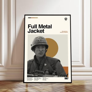 May include: A framed poster for the film "Full Metal Jacket" featuring a soldier in a helmet and glasses. The poster has a beige background with the film title in bold black letters and the year 1987. Directed by Stanley Kubrick.