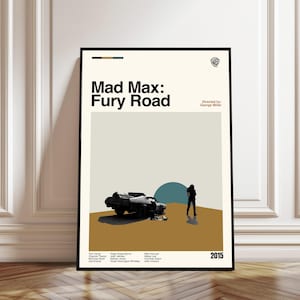 May include: A framed poster for the movie "Mad Max: Fury Road." The poster features a minimalist design with a wrecked vehicle, a silhouetted figure, and the film's title. The color palette includes beige, brown, and teal.