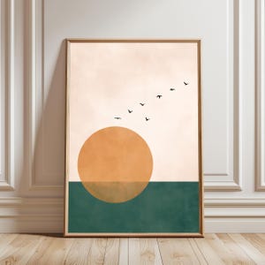 May include: A rectangular wall art print featuring a large orange circle representing a sun positioned over a solid dark green horizontal band. Above the sun, a flock of six small black birds flies across a pale beige background.