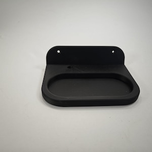 Puede incluir: Estante negro para montaje en pared con una bandeja ovalada y una parte trasera plana. El estante tiene dos agujeros en la parte superior para el montaje. El diseño es simple y moderno, adecuado para guardar objetos pequeños.