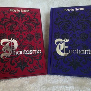 May include: Two hardback books with elaborate black patterns on red and blue covers. The red book is titled "Phantasma" and the blue book is "Enchantra". Both books display the author's name, "Kaylie Smith", at the top.