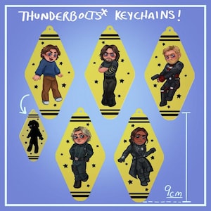 Puede incluir: Llaveros amarillos en forma de diamante con ilustraciones de personajes de dibujos animados. Los llaveros miden aproximadamente 9 cm de largo, con rayas negras y estrellas. El texto "THUNDERBOLTS KEYCHAINS!" está en la parte superior.
