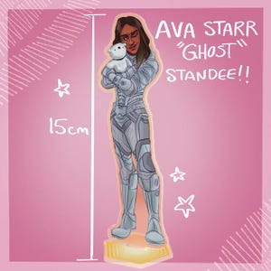 Può includere: Un espositore di Ava Starr, da "Ghost", che tiene in braccio un piccolo peluche bianco. L'illustrazione è in stile futuristico, con il personaggio che indossa una tuta argentata e grigia. L'espositore è alto 15 cm e su sfondo rosa.