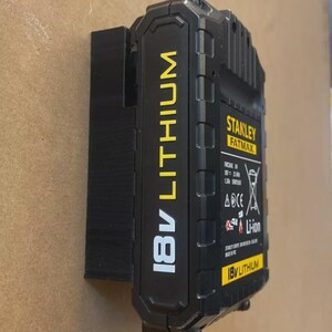 May include: Black and yellow 18V Lithium battery pack for power tools. The battery pack has the "STANLEY FATMAX" logo and "18V LITHIUM" text. The battery pack is mounted on a black plastic holder.