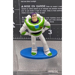 Mini figura di Buzz Lightyear di Toy Story della Mattel, base ovale blu, mani sui fianchi allentate immagine 1