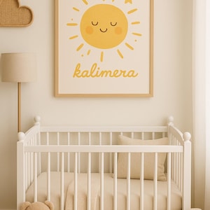 Op de afbeelding: Een kinderkamer met een witte wieg, beige beddengoed en een ingelijste print van een gele zon met het woord "kalimera". Een teddybeer en een maankussen zijn ook aanwezig. De kamer heeft een rustige, neutrale uitstraling.